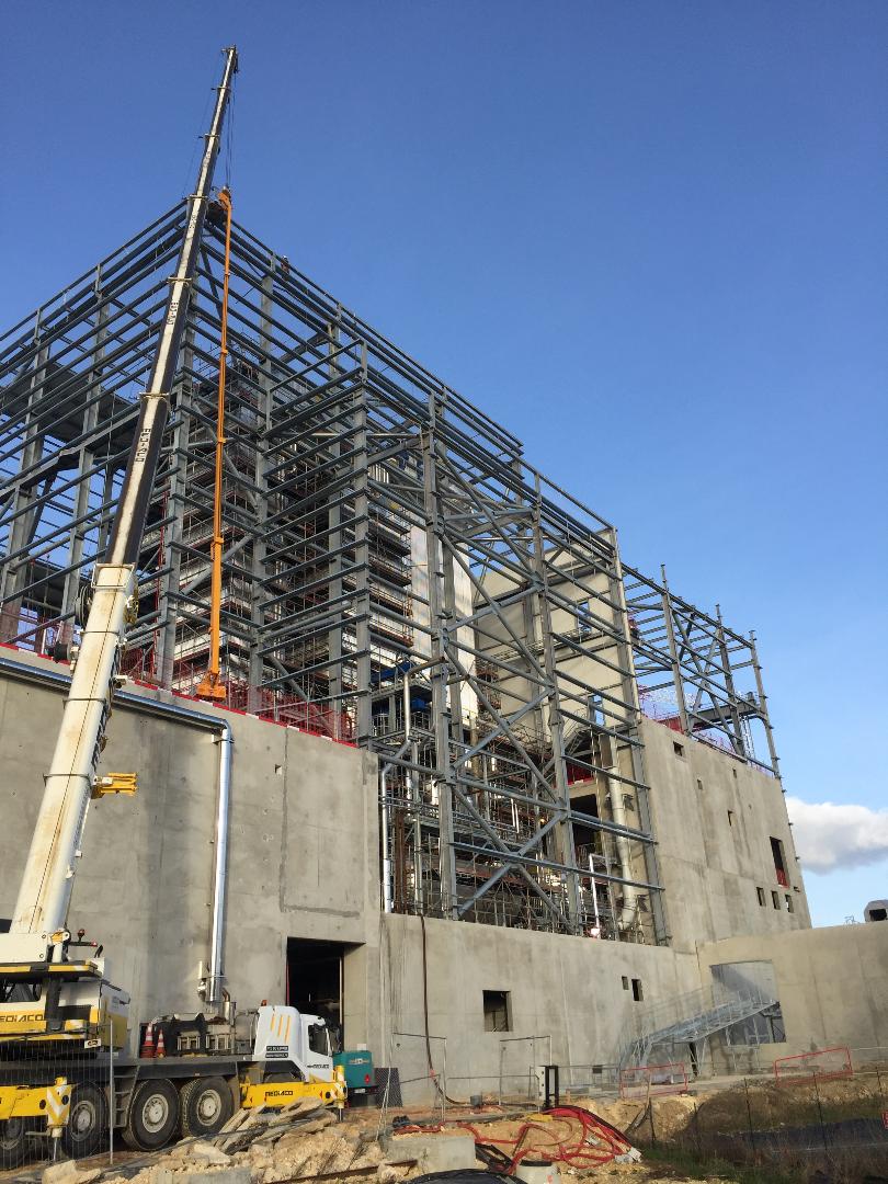 Un ascenseur orange permet à un ouvrier d'ajuster la structure, créant ainsi une impression de progrès.