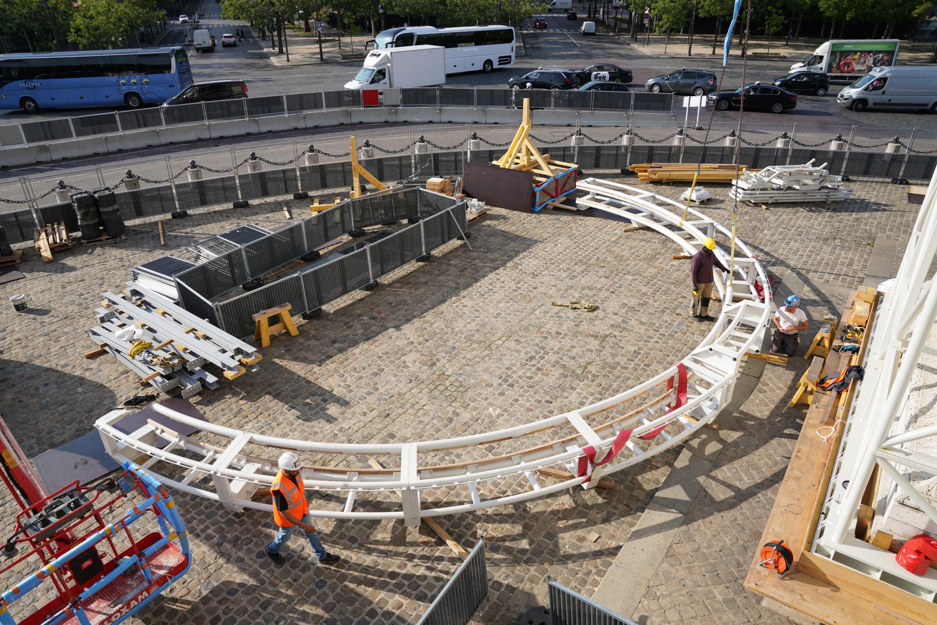 Deux ouvriers du bâtiment en tenue de sécurité manœuvrent une grue sur un toit avec un horizon urbain en arrière-plan.